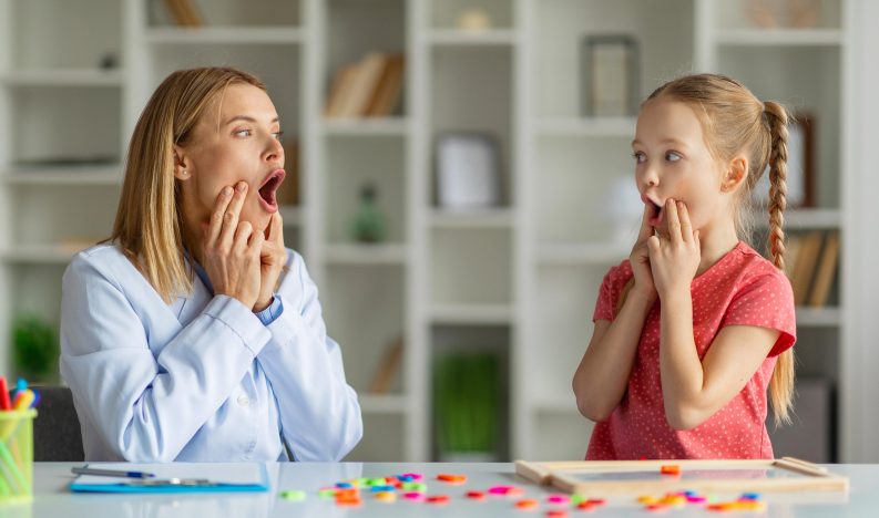 Speech Therapist Woman Making Articulation Exercises With Little Girl At Therapy Session, Cute Preteen Female Child Working On Pronunciation With Logopedist Lady During Meeting In Office